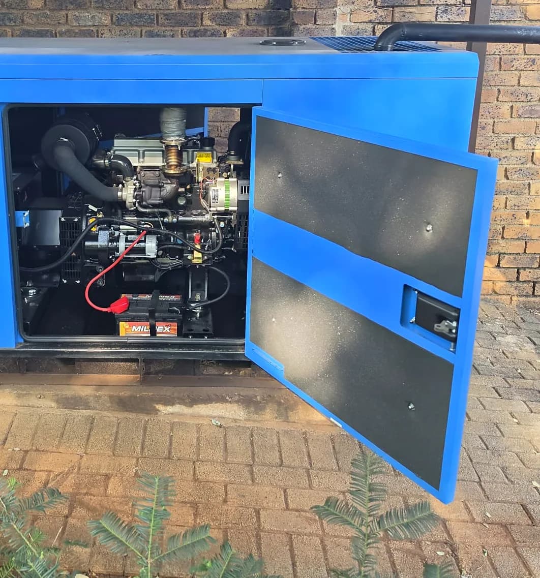 Open door of a blue silent diesel generator showing the engine and the starting battery with its red terminal cover